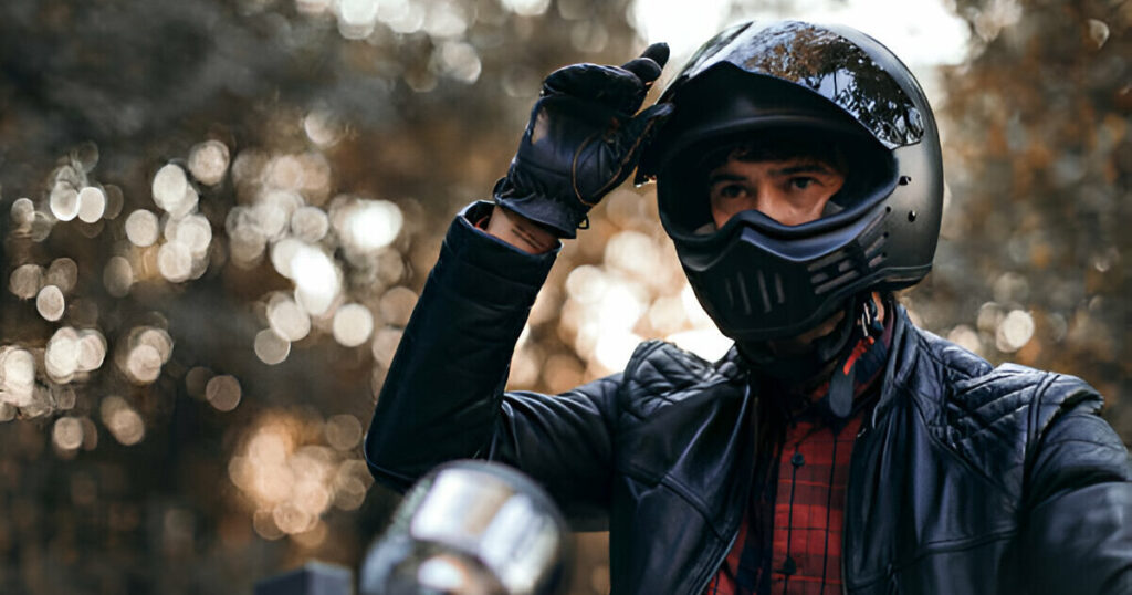 A person puts on his dirt bike helmet