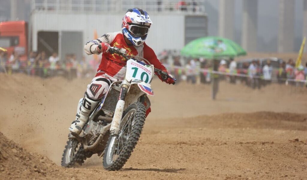 Piloto de bicicleta suja andando em uma partida de motocross