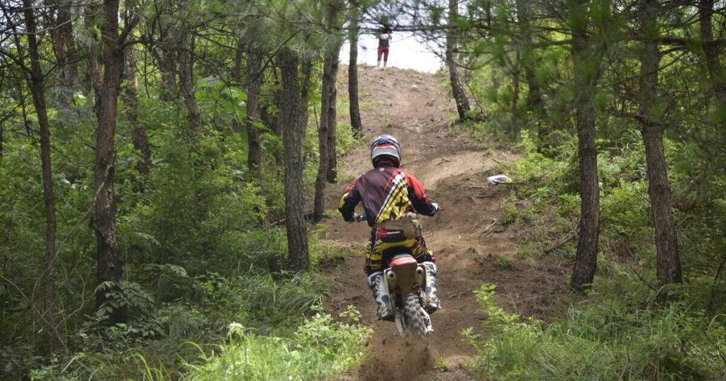 Cavalier de moto tout-terrain circulant dans les bois de montagne