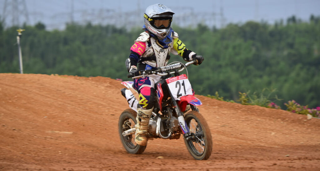 Joven principiante en moto de cross conduciendo una moto de cross de 4 tiempos